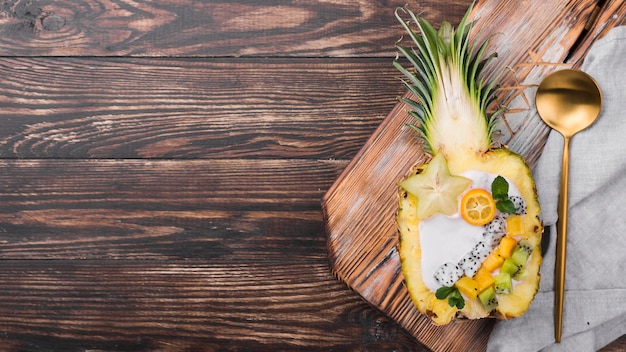 Goldener Löffel und Obstsalat in der Hälfte der Ananas