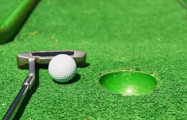 Golfball und Golfschläger auf Kunstrasen.