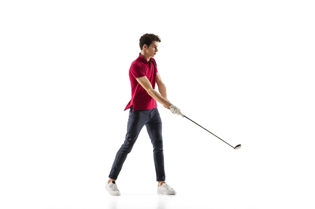 Golfspieler in einem roten Hemd, das einen Schlag lokalisiert auf weißem Studiohintergrund nimmt