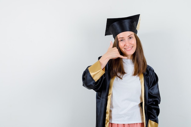 Graduierte Frau in Freizeitkleidung, Uniform, die Telefongeste zeigt und selbstbewusst, Vorderansicht schaut.