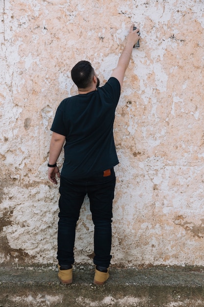 Graffitikünstler, der mit Spraydose auf schmutziger Wand malt