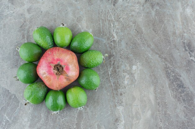 Kostenloses Foto granatapfel von feijoas auf marmor umgeben.