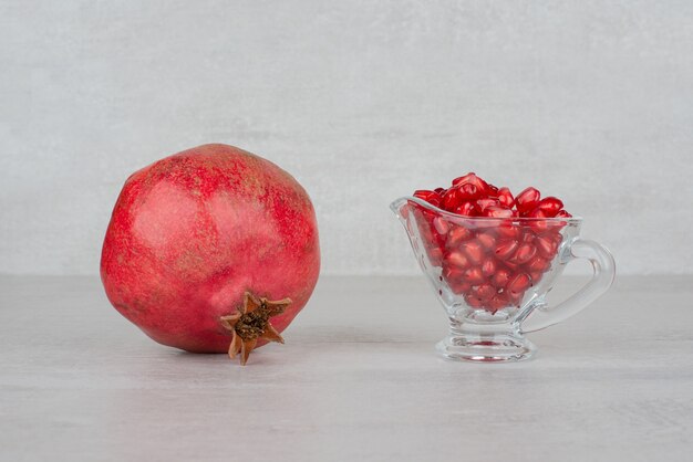 Kostenloses Foto granatapfelkerne in glas und granatapfel auf weiß.