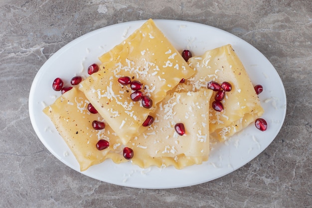 Granatapfelkerne mit Lasagneblättern auf dem Teller, auf dem Marmor.