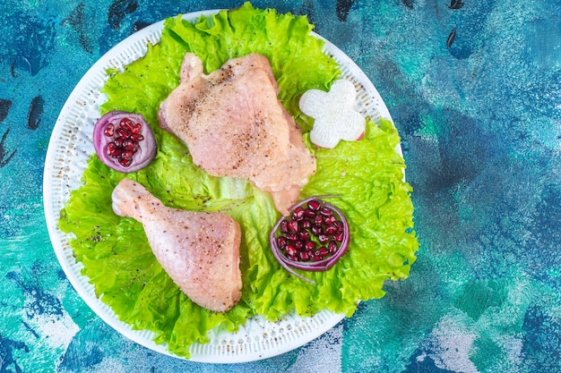 Granatapfelkerne, Salatblätter mit Zwiebelring neben Hühnerfleisch auf einem Teller