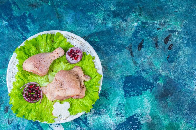 Granatapfelkerne, Salatblätter mit Zwiebelring neben Hühnerfleisch auf einem Teller