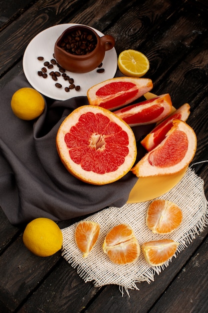 Grapefruit und Zitrone geschnittene Mandarinen zusammen mit Kaffeesamen auf dem braunen Holz rustikal