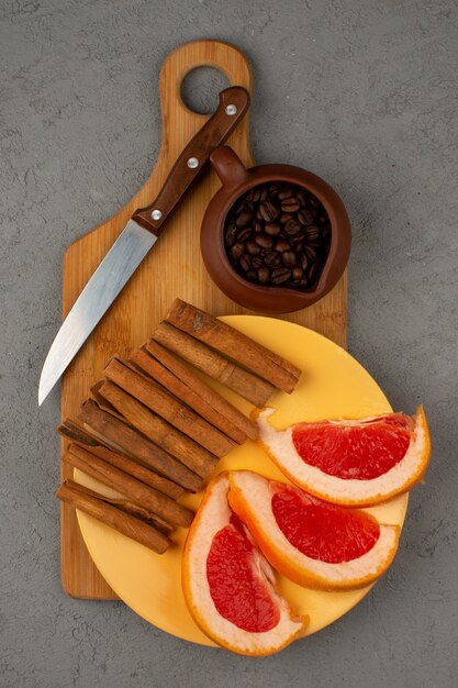 Grapefruit-Zimt-Kaffee innerhalb der gelben Platte auf einem braunen Holzschreibtisch auf einem grauen Boden