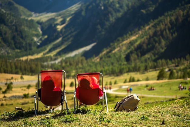 Grasfeld mit zwei Personen, die auf Stühlen liegen und die Aussicht genießen