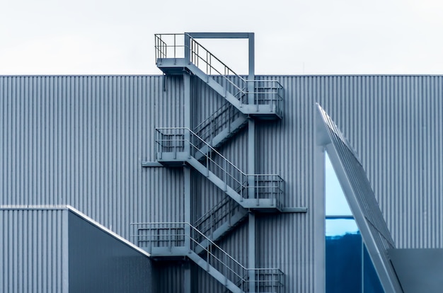 Graue Metallwand mit Wendeltreppe unter dem klaren Himmel