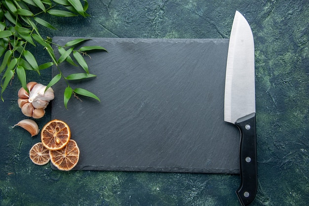 Graue Platte der Draufsicht mit großem Messer auf dunkelblauem Hintergrundfarbfoto kochen blauen Meeresfrüchte-Küchenschreibtisch