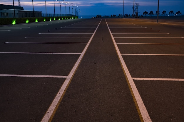 Graue Straße mit weißen Linien und Zeichen gegen blauen Himmel