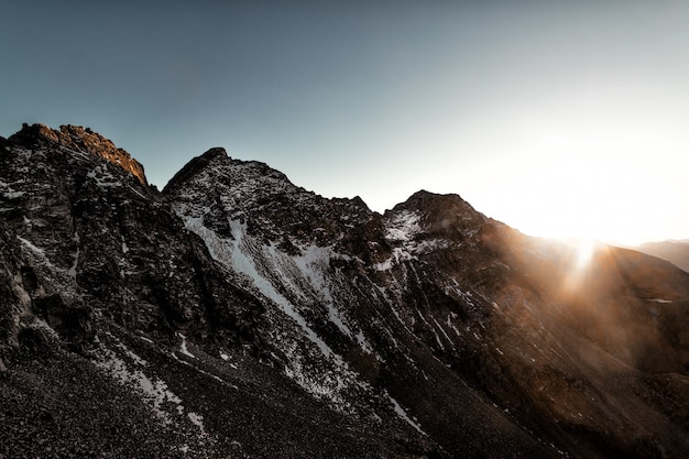 Grauer Felsenberg mit weißem Schnee während der Sonnenaufgang-Luftgrafik