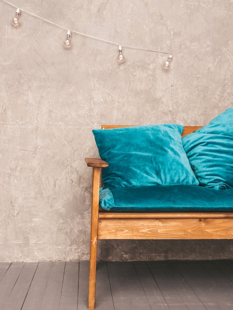 Grauer Wandinnenraum mit stilvollem gepolstertem blauem und hölzernem modernem Sofa