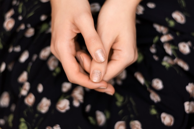 Graues Nageldesign. Weibliche Hand mit Glitzer-Maniküre.