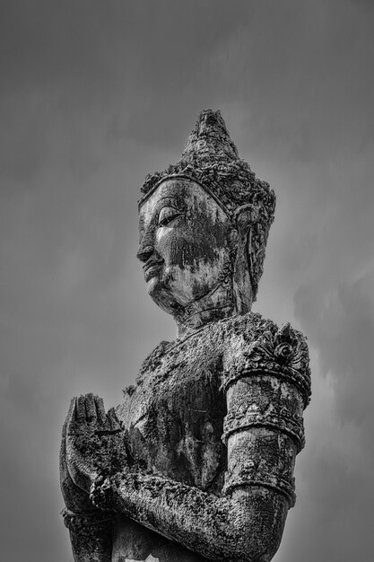 Graustufenaufnahme einer Buddha-Statue unter dem dunklen Himmel
