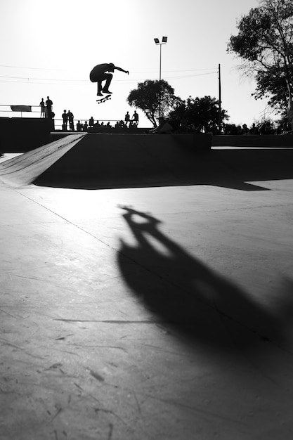 Graustufenaufnahme eines Mannes, der Tricks mit einem Skateboard tut