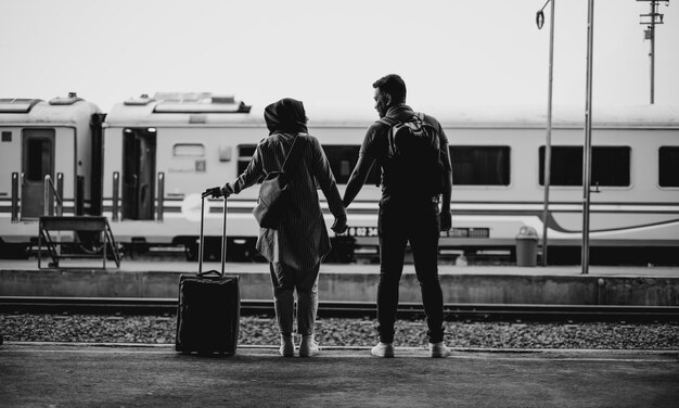 Graustufenaufnahme eines Paares, das in einem Bahnhof steht