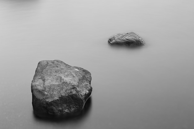 Graustufenaufnahme von Felsformationen im gefrorenen Ozean, der mit Nebel bedeckt ist