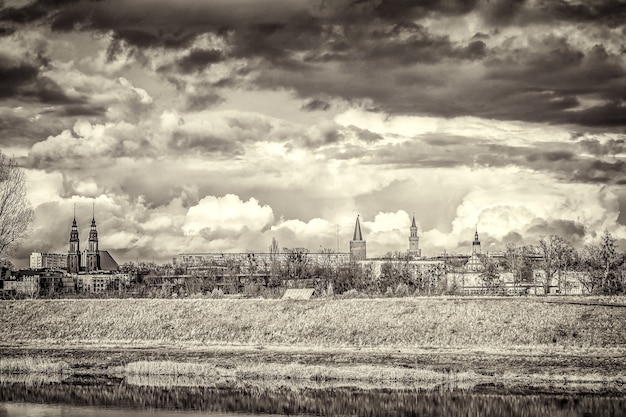 Kostenloses Foto graustufenaufnahme von gebäuden in der ferne unter einem bewölkten himmel