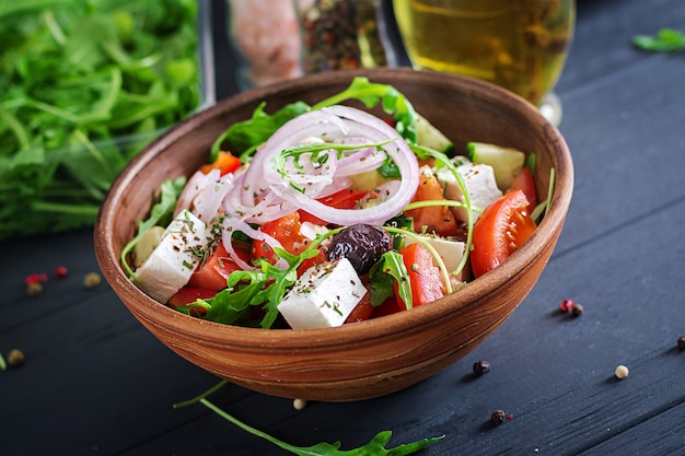 Griechischer salat mit frischen tomaten, gurken, roten zwiebeln, basilikum, feta, schwarzen oliven und italienischen kräutern