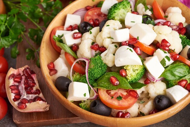 Griechischer Salat oder Horiatiki mit großen Stücken von Tomaten, Gurken, Zwiebeln, Feta-Käse und Oliven in der weißen Schüssel isolierte Draufsicht. Dorfsalat mit gewürfeltem Mozzarella, Rucola, Petersilie und Olivenöl