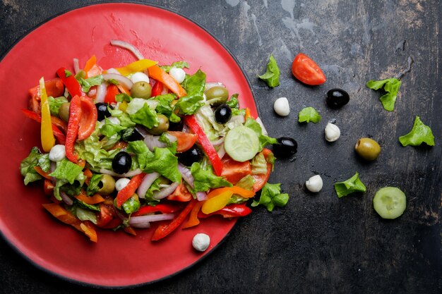 Griechischer Salat von oben mit Tomaten- und Oliven- und Käsefeta in roter Platte