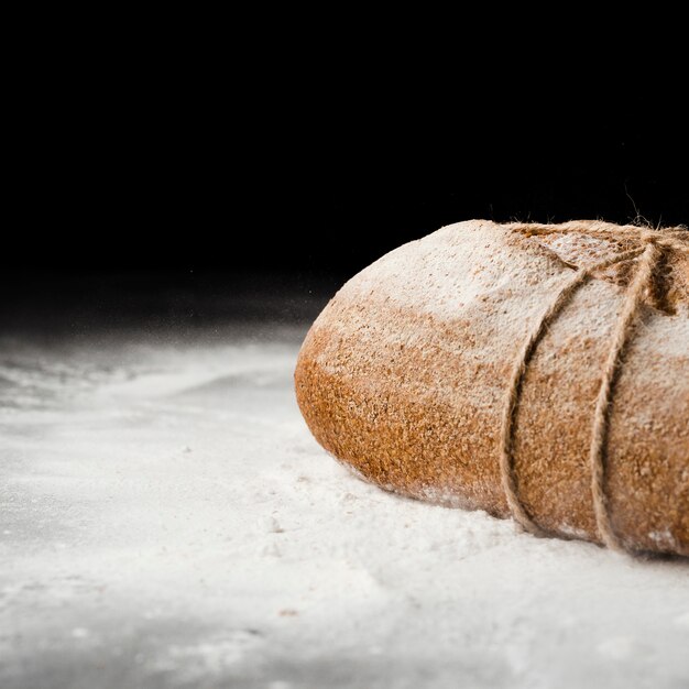 Großaufnahme des Brotes und des Mehls auf schwarzem Hintergrund