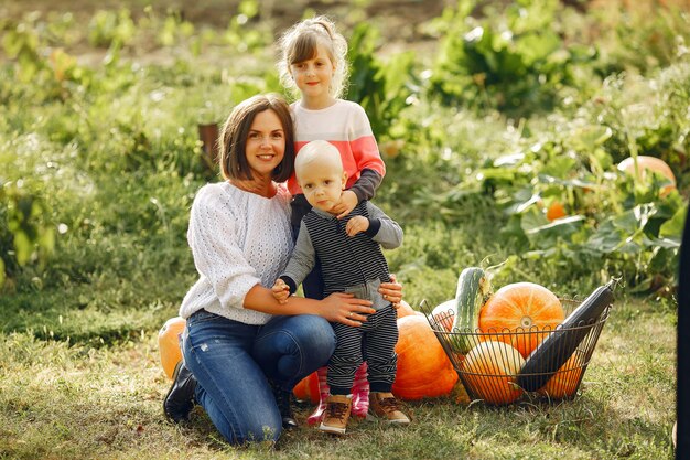 Große Familie, die auf einem Garten nahe vielen Kürbisen sitzt