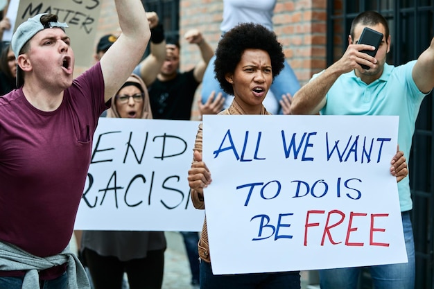 Große Gruppe von Menschen, die auf den Straßen gegen Rassismus demonstrieren Der Fokus liegt auf einer schwarzen Frau, die ein Plakat mit der Aufschrift "Freiheit" trägt