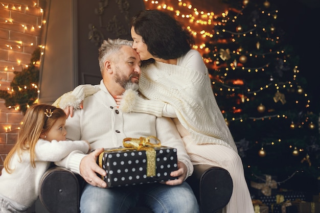 Großeltern sitzen mit ihrer Enkelin. Weihnachten feiern in einem gemütlichen Haus.