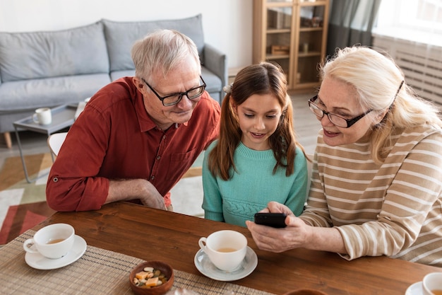 Großeltern und Mädchen schauen auf Telefon