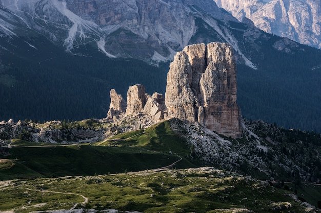 Großer Felsen auf einem grasbewachsenen Hügel mit bewaldeten Bergen