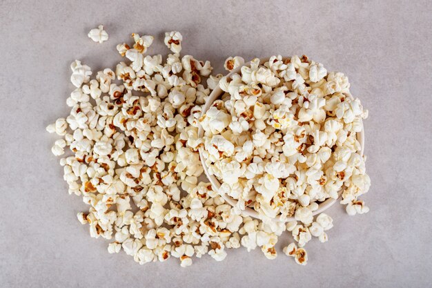 Großer Haufen Popcorn, der eine Schüssel auf Marmor vollständig bedeckt.