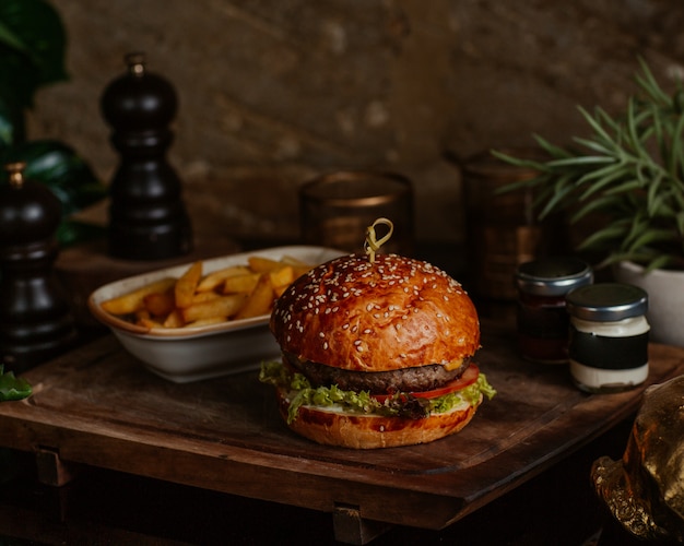 Kostenloses Foto großer portionsrindfleischburger mit pommes-frites und dip-sauce in einem café