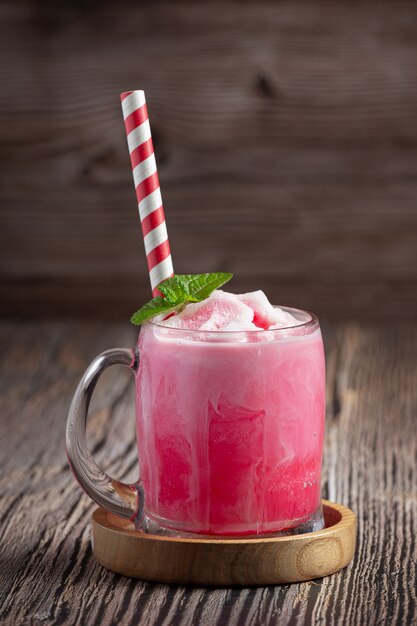 großes Glas Erdbeermilchshake mit bunten Strohhalmen