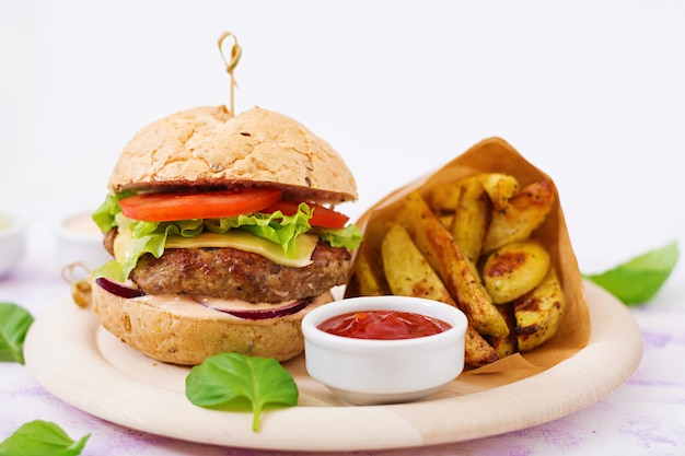 Großes Sandwich - Hamburger mit saftigem Rindfleischburger, Käse, Tomaten, roten Zwiebeln und Pommes Frites.