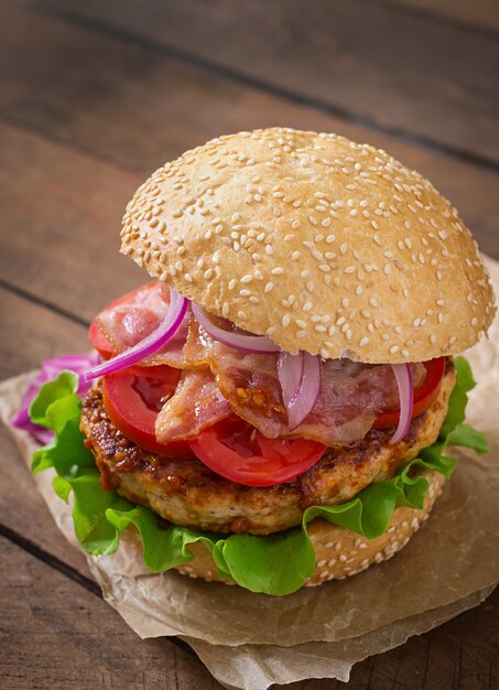 Großes Sandwich - Hamburgerburger mit Rindfleisch, roter Zwiebel, Tomate und gebratenem Speck.