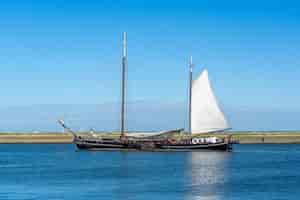 Kostenloses Foto großes segelboot mit weißen segeln auf der wasseroberfläche unter strahlend blauem himmel