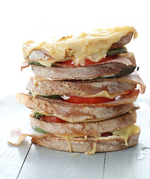 Großes veganes Sandwich mit Gemüse und Käse auf Holzbretttisch