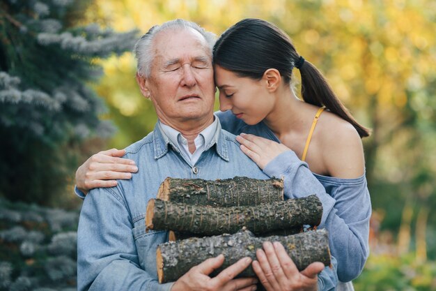 Großvater mit Enkelin auf einem Hof mit Brennholz in Händen