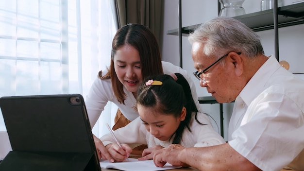Großvater und mutter unterrichten tochter hausaufgaben, während sie zu hause online lernen.