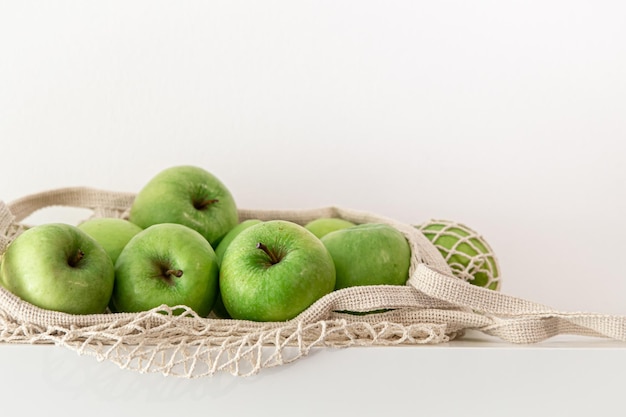 Grüne äpfel in einer schnurtasche auf weißem hintergrund