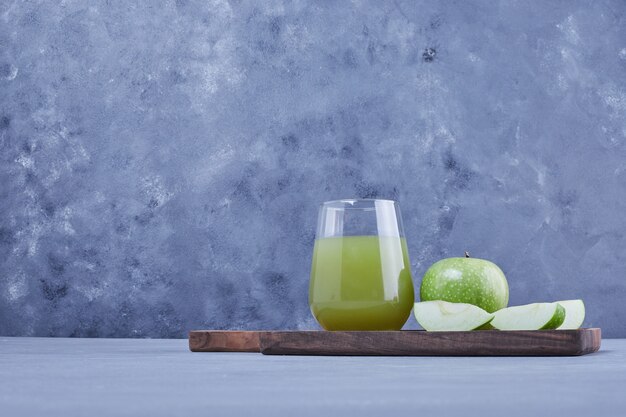 Grüne Apfelscheiben mit einem Glas Saft.