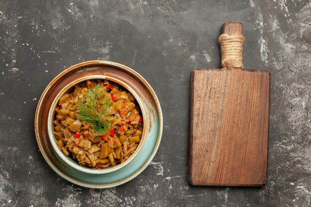 grüne Bohnen mit Tomaten Schüssel mit den appetitlichen grünen Bohnen mit Tomaten neben dem Schneidebrett auf dem Tisch