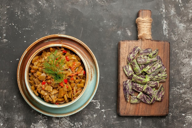 Grüne bohnen mit tomaten schüssel mit den appetitlichen tomaten und grünen bohnen neben dem schneidebrett mit grünen bohnen auf dem tisch