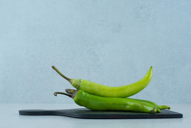 Grüne Chilischoten auf dunklem Brett.