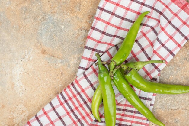 Grüne Chilischoten auf Tischdecke auf Marmoroberfläche