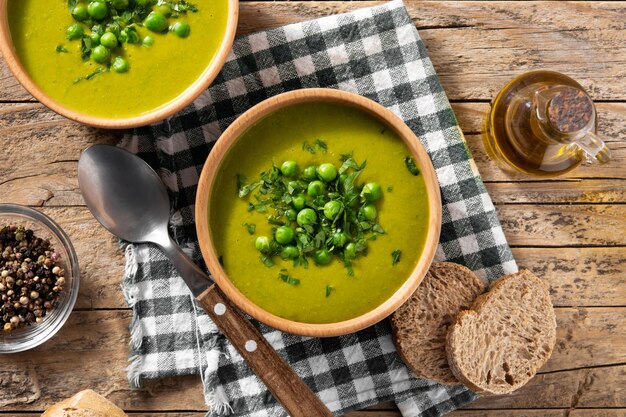 Grüne Erbsensuppe in einer Schüssel auf Draufsicht des rustikalen Holztischs