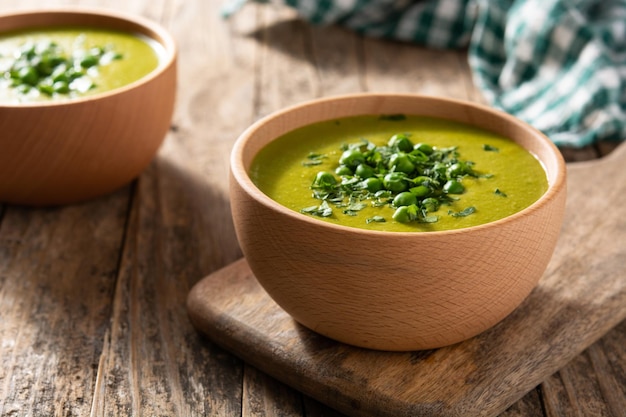 Grüne Erbsensuppe in einer Schüssel auf Holztisch